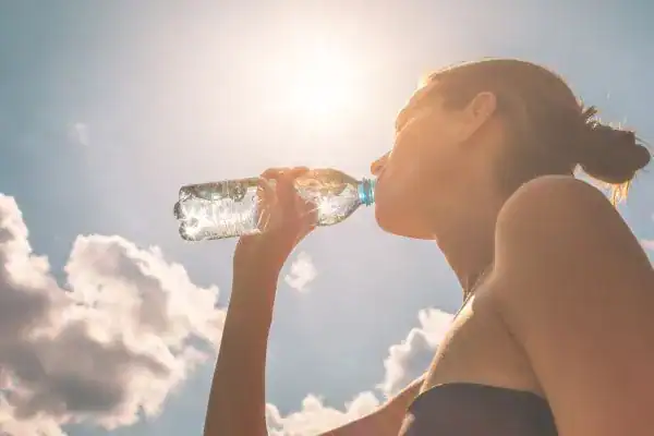 Hydration: The Secret Ingredient for a Toned Stomach and Enhanced Fitness 3 Image of woman drinking water to hydrate Busby after run.