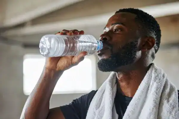 Image of man drinking water to improve hydration Busby after work out.